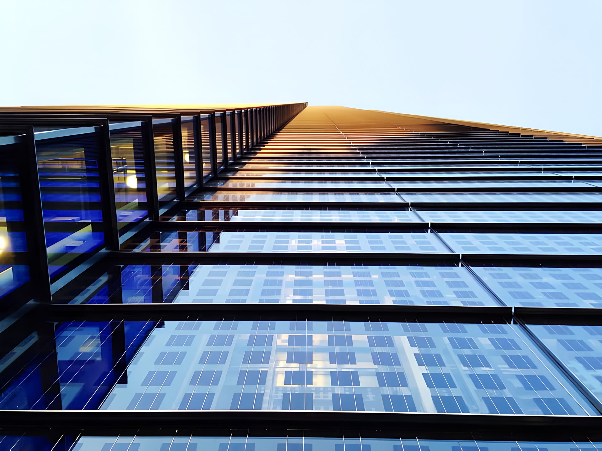 Looking up a dark modern tower at sunset